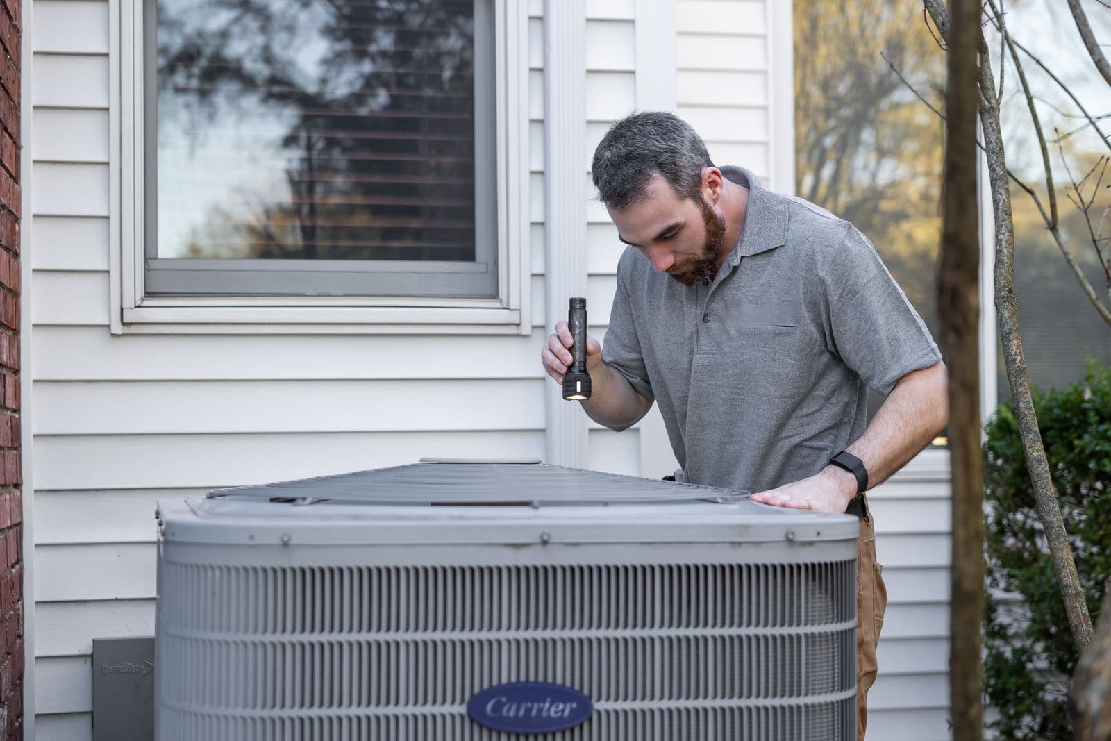A service technician on the phone beside rooftop condenser units