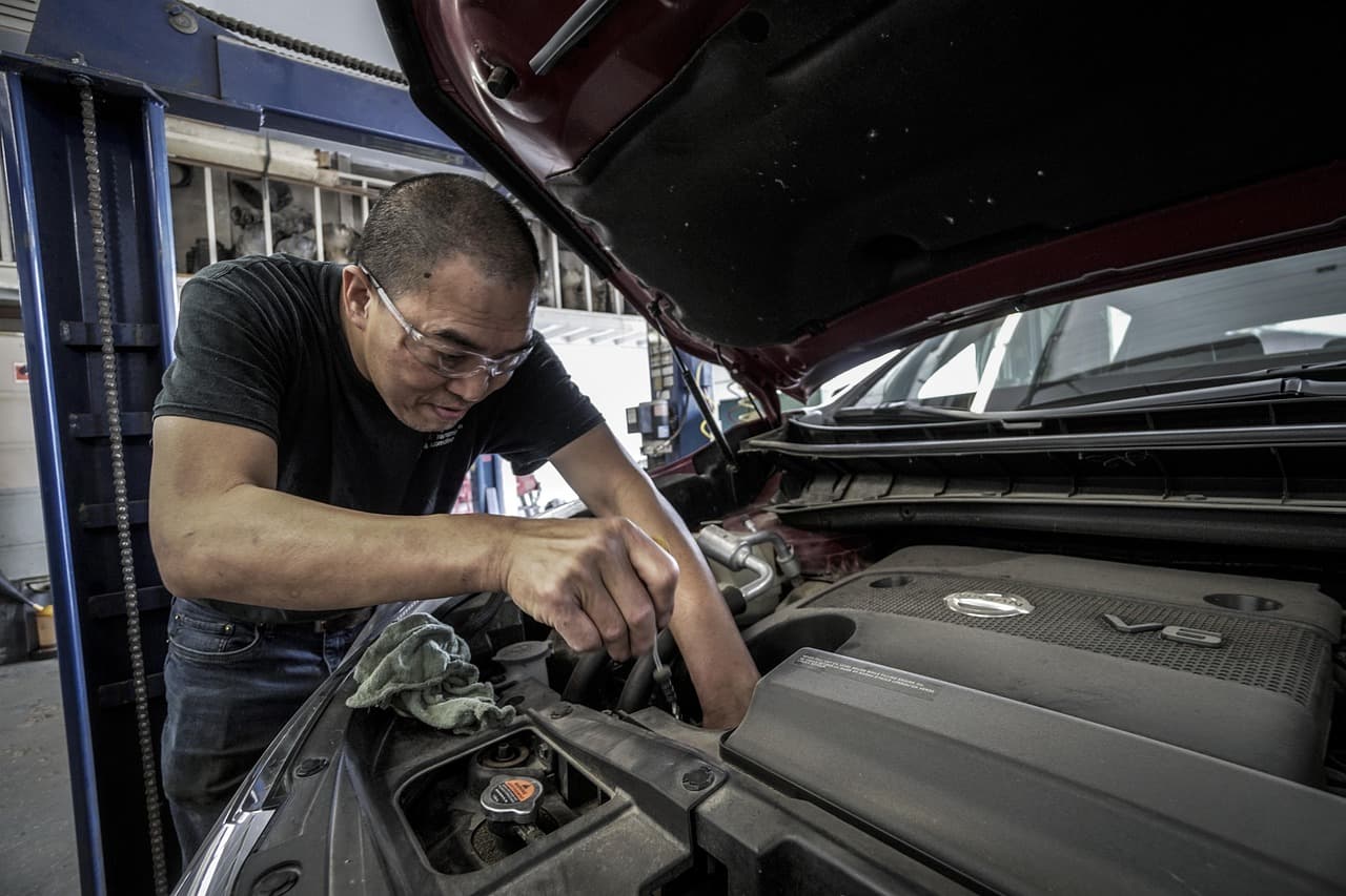 A mechanic working under the hood of a car